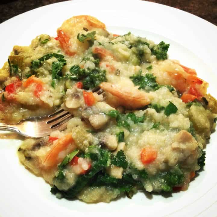 Garlic shrimp and kale risotto on a white plate