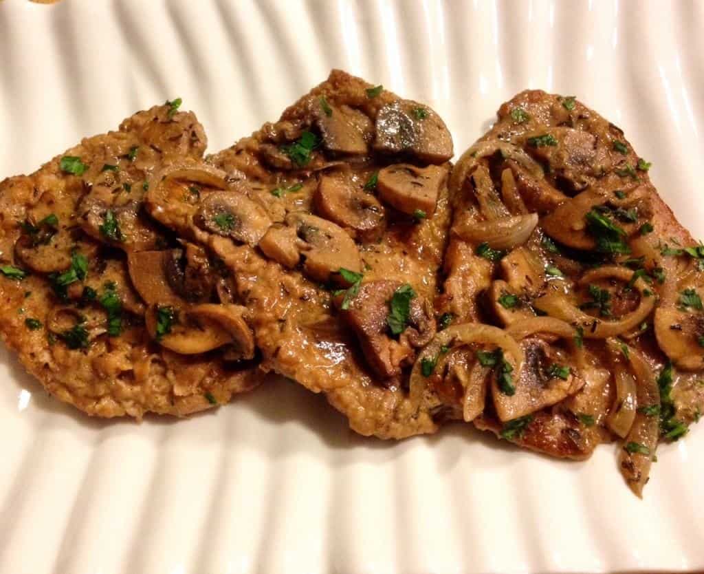 Veal Marsala covered with mushrooms on a white plate