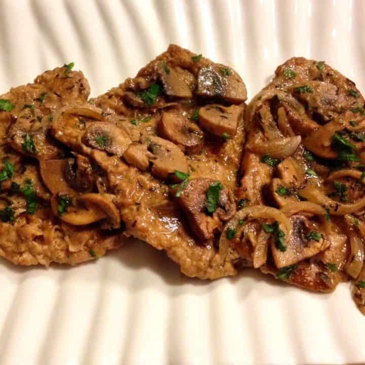 Veal Marsala covered with mushrooms on a white plate