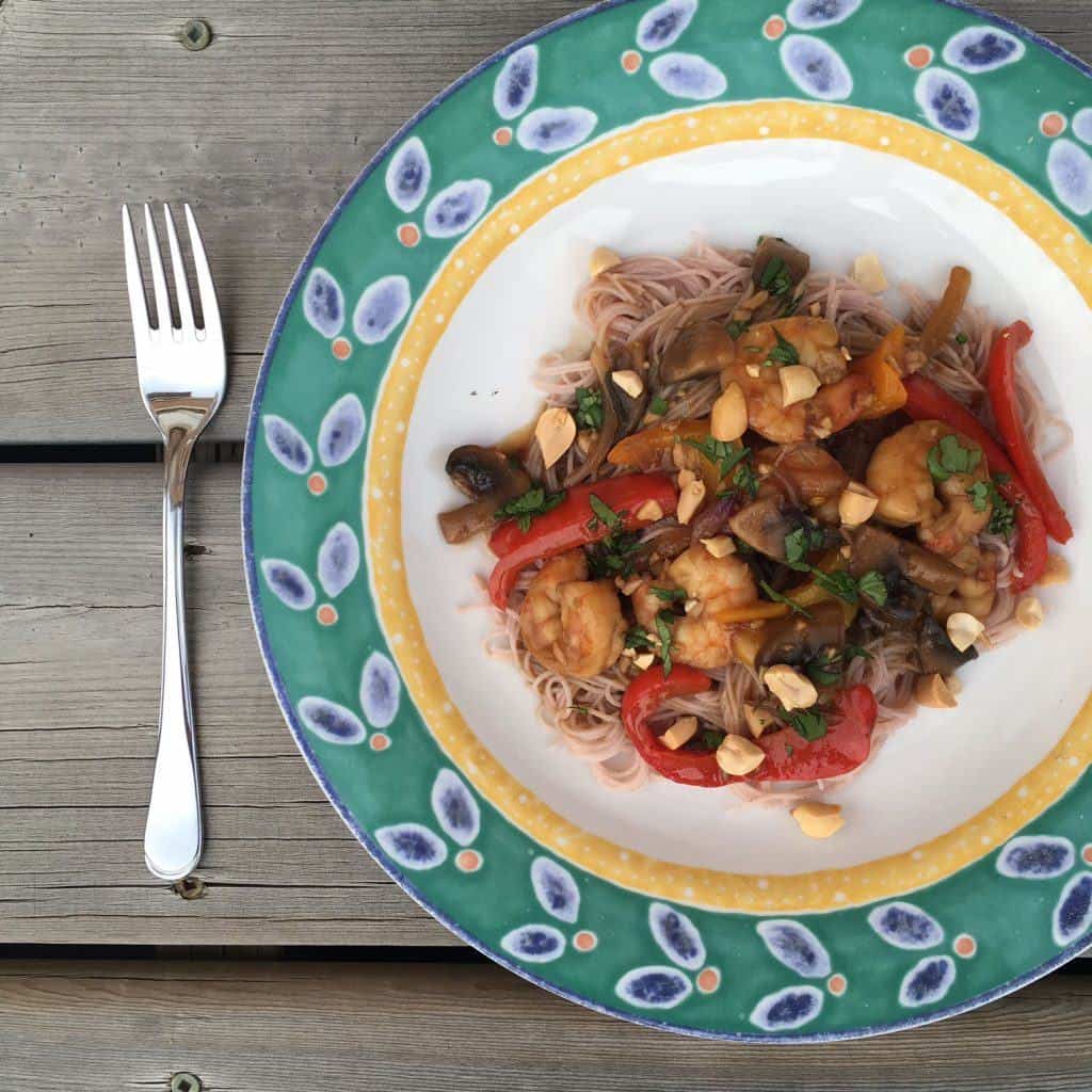 Shrimp, red peppers and peanuts in a turquoise bowl, with a fork on the left