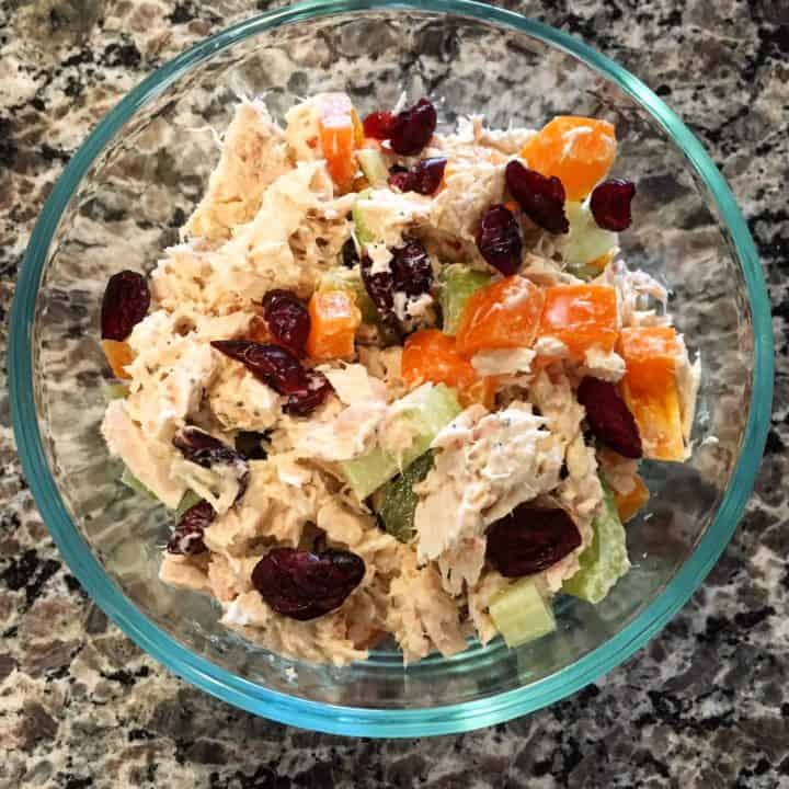 tuna salad with carrots, celery and raisins in a glass bowl