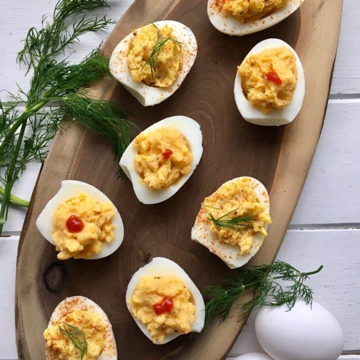Deviled eggs on a wooden platter with a white background, perfect hard boiled eggs