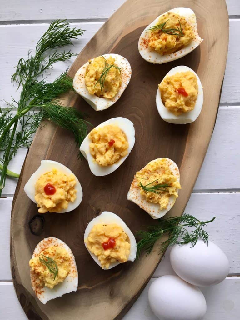 Deviled eggs on a wooden platter with a white background, perfect hard boiled eggs