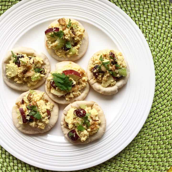 curry egg salad on whole wheat mini pizzas on a white plate