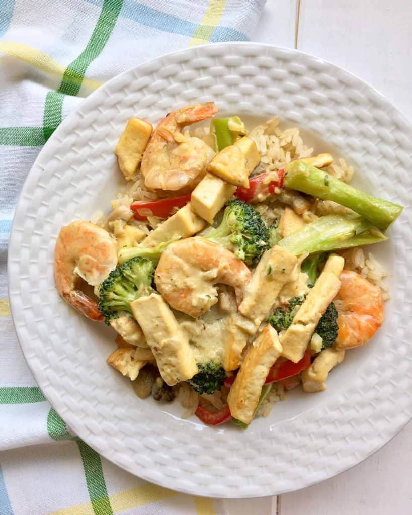 Fry featuring broccoli, shrimp, and tofu on a white textured plate.