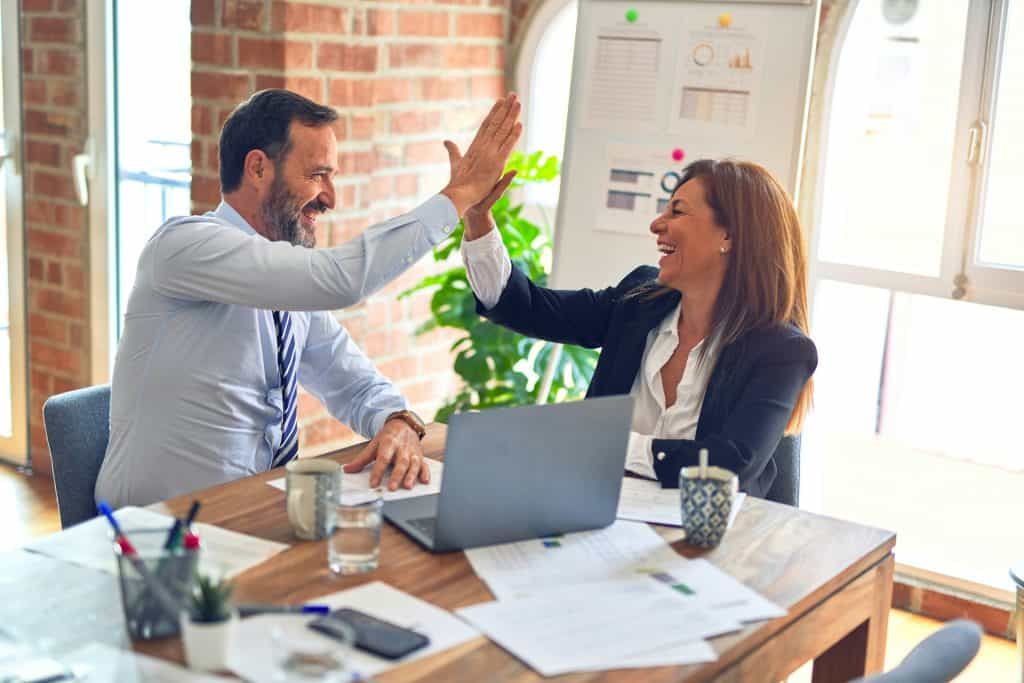 Two professionals high-fiving in an office, discussing nutrition strategies.